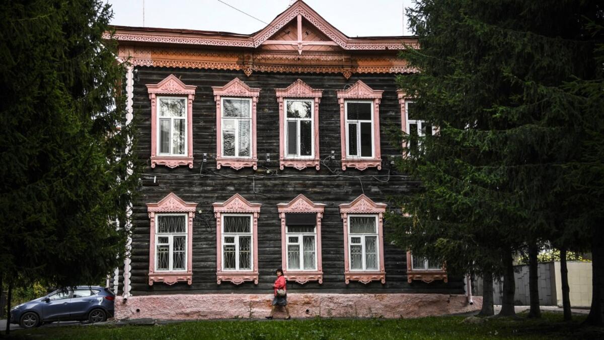A woman walks past a traditional wooden house in the Siberian city of Tomsk on September 8, 2020. Tomsk is considered to be one of the oldest towns in Siberia founded in 1604. Wooden architecture is one of the symbols of the city of Tomsk, its distinctive feature. Today Tomsk is the only city in Siberia where the background wooden buildings have been preserved, reflecting the manor structure of the city streets. Unfortunately, many wooden houses are not in very good condition and require restoration. Alexan