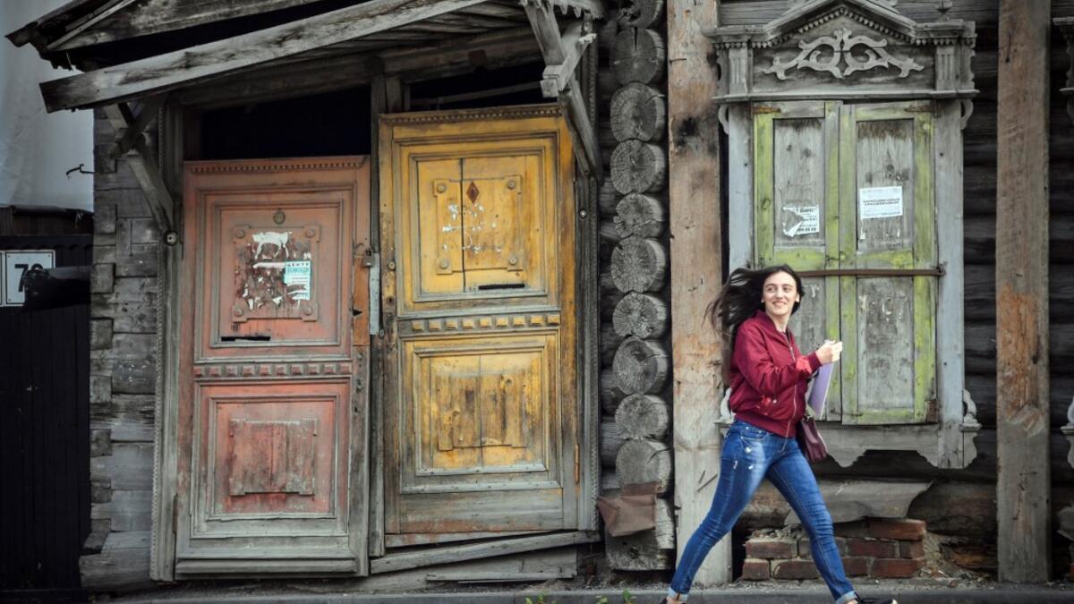 A woman walks past a traditional wooden house in the Siberian city of Tomsk on September 8, 2020. Tomsk is considered to be one of the oldest towns in Siberia founded in 1604. Wooden architecture is one of the symbols of the city of Tomsk, its distinctive feature. Today Tomsk is the only city in Siberia where the background wooden buildings have been preserved, reflecting the manor structure of the city streets. Unfortunately, many wooden houses are not in very good condition and require restoration. Alexan