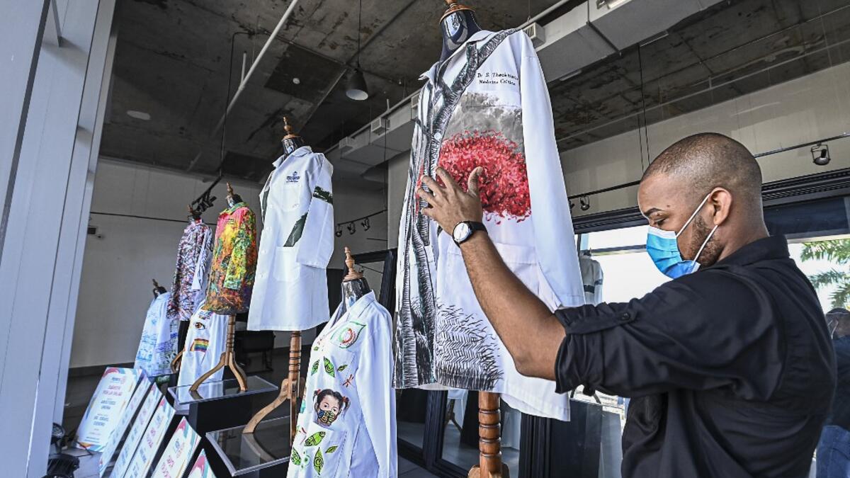 A gallery worker organizes white coats used by doctors fighting against COVID-19 and decorated by Panamanian artists, in Panama City, on September 26, 2020. More than 20 doctor's coats fighting against COVID-19 that were disinfected and painted by Panamanian artists will be auctioned off from October 1 to 4. The funds will go to 20 health centers. Luis ACOSTA / AFP
