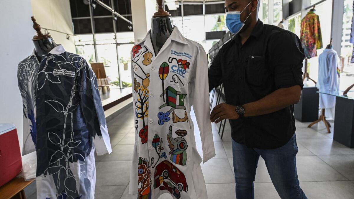 A gallery worker organizes white coats used by doctors fighting against COVID-19 and decorated by Panamanian artists, in Panama City, on September 26, 2020. More than 20 doctor's coats fighting against COVID-19 that were disinfected and painted by Panamanian artists will be auctioned off from October 1 to 4. The funds will go to 20 health centers. Luis ACOSTA / AFP