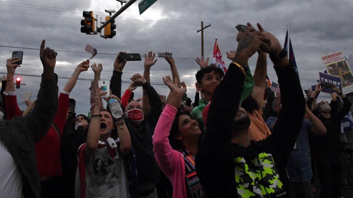 Supporters cheer as Marine One carrying the US President leaves Walter Reed Medical Center in Bethesda, Maryland on October 5, 2020, to return to the White House after the president was discharged. Trump announced Monday he would be "back on the campaign trail soon", just before returning to the White House from a hospital where he was being treated for Covid-19. Olivier DOULIERY / AFP