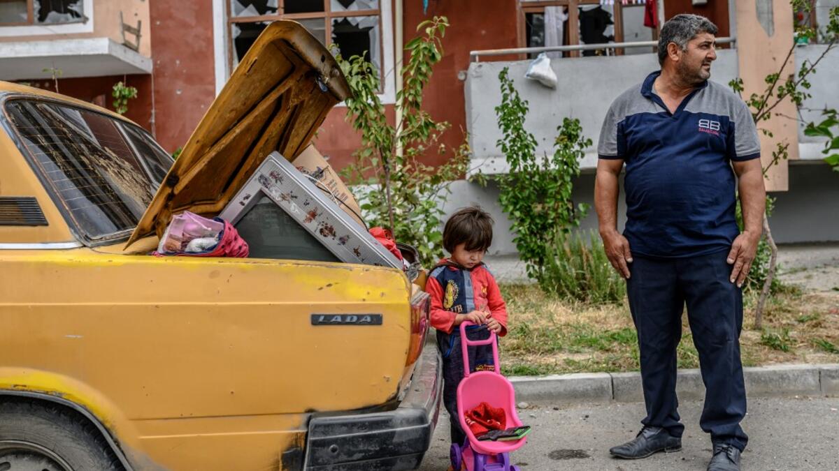 A man stands with his kid by a car outside a damaged apartment building after the family took their last belongings from their flat during a ceasefire during a military conflict between Armenia and Azerbaijan over the breakaway region of Nagorno-Karabakh, in the town of Terter, Azerbaijan, on October 10, 2020. Armenia and Azerbaijan traded accusations of new attacks on October 10 in breach of a ceasefire deal to end nearly two weeks of heavy fighting over the disputed Nagorno-Karabakh region. Bulent Kilic /
