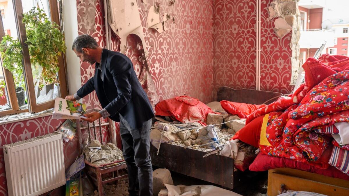 Yasin Budakov, 40, holds a book which his kid forgot to take when they were running out of his damaged flat as residents return to their homes following a ceasefire during a military conflict between Armenia and Azerbaijan over the breakaway region of Nagorno-Karabakh, in the town of Terter, Azerbaijan, on October 10, 2020. Armenia and Azerbaijan traded accusations of new attacks on October 10 in breach of a ceasefire deal to end nearly two weeks of heavy fighting over the disputed Nagorno-Karabakh region.