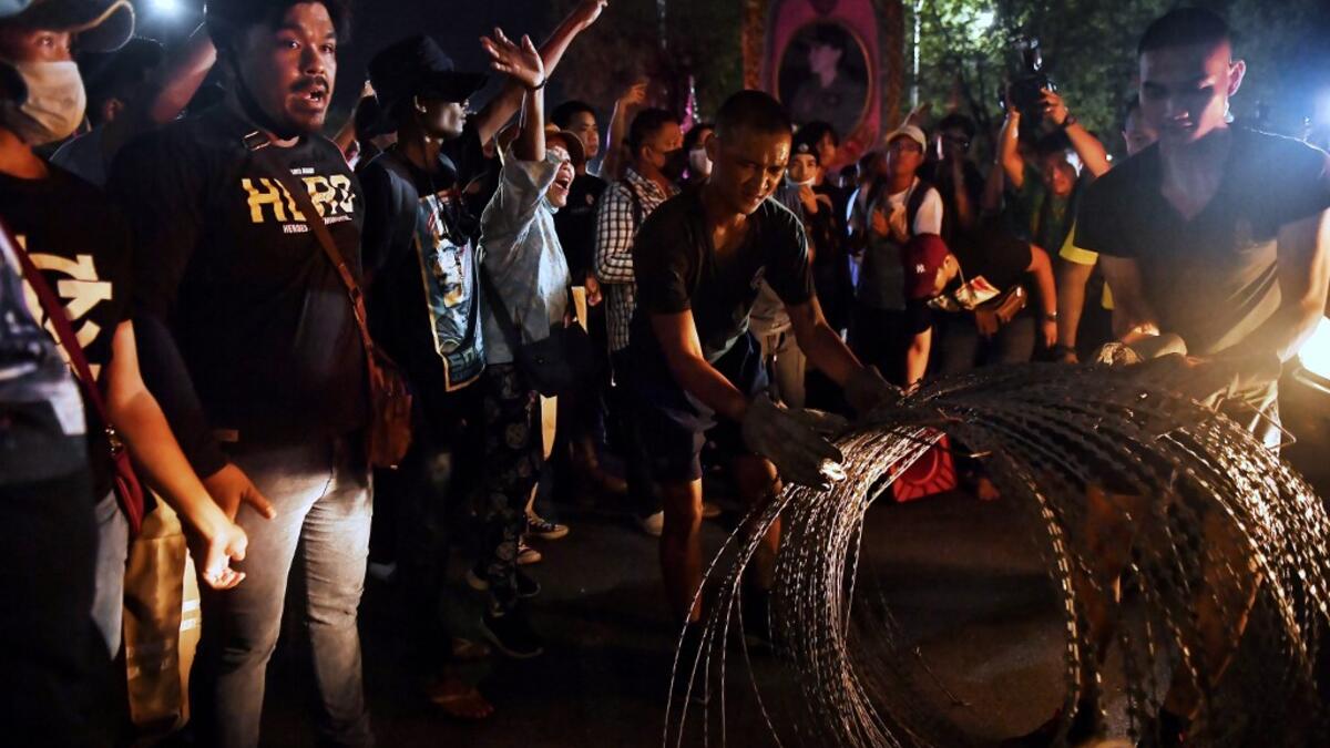 Pro-democracy protesters heckle soldiers as they are deterred from installing razor wire on the road in front of the Royal Thai Army headquarters in Bangkok on October 14, 2020. Lillian SUWANRUMPHA / AFP