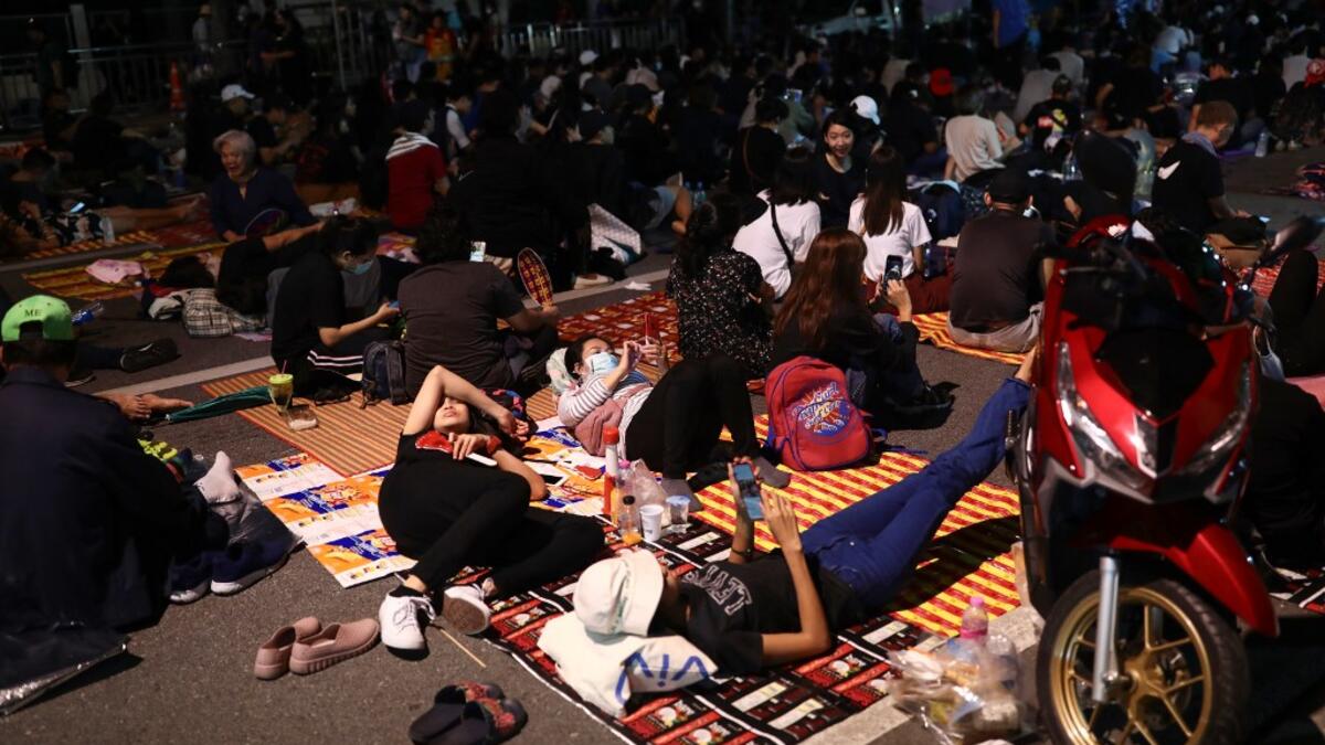 Pro-democracy protesters rest on the ground during an anti-government rally next to Government House in Bangkok on October 14, 2020. Jack TAYLOR / AFP