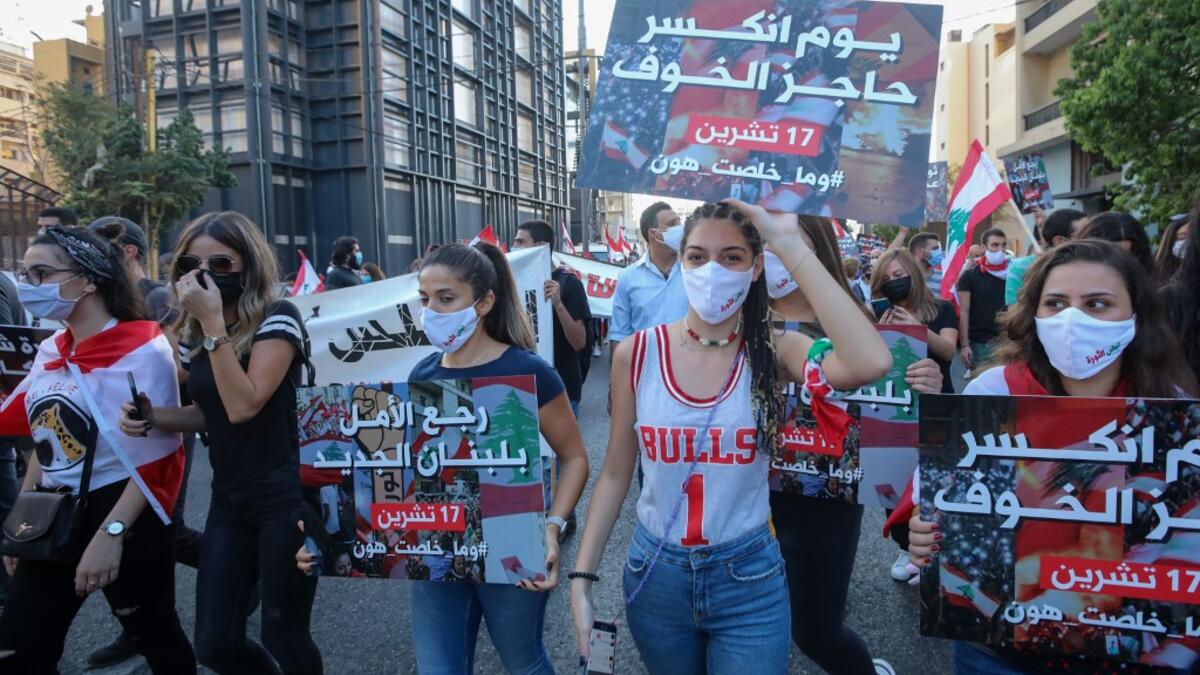 Lebanese protesters lift placards during a demonstration marking the one year anniversary of the beginning of a nationwide anti-government protest movement, in the capital Beirut on October 17, 2020. Hundreds marched in Lebanon's capital to mark the first anniversary of a non-sectarian protest movement that has rocked the political elite but has yet to achieve its goal of sweeping reform. ANWAR AMRO / AFP