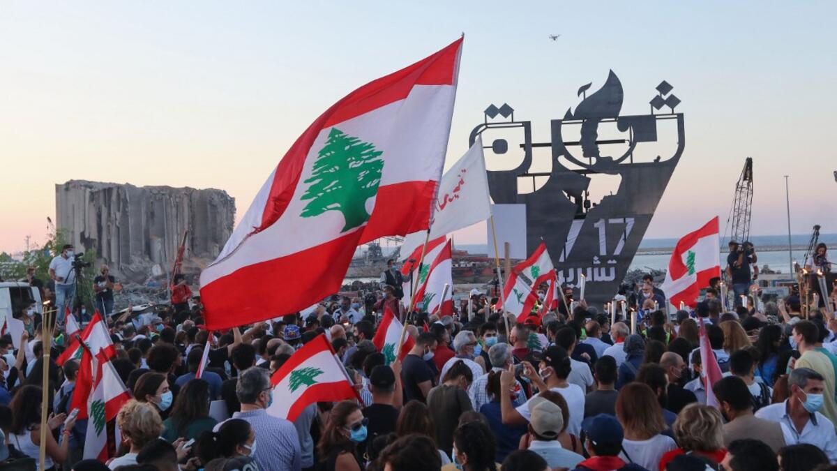Lebanese protesters gather to light the "October 17 torch" marking the one year anniversary of the beginning of a nationwide anti-government protest movement, in front of the devastated port of the capital Beirut where a massive explosion took place more than two months ago, on October 17, 2020. ANWAR AMRO / AFP