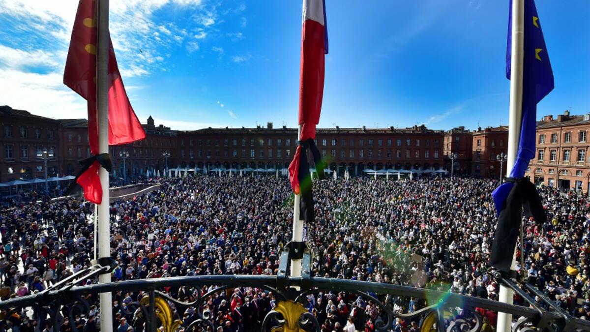 Flags of the City hall are at half-mast as people gather on Place du Capitole in Toulouse on October 18, 2020, in homage to history teacher Samuel Paty two days after he was beheaded by an attacker who was shot dead by policemen. GEORGES GOBET / AFP