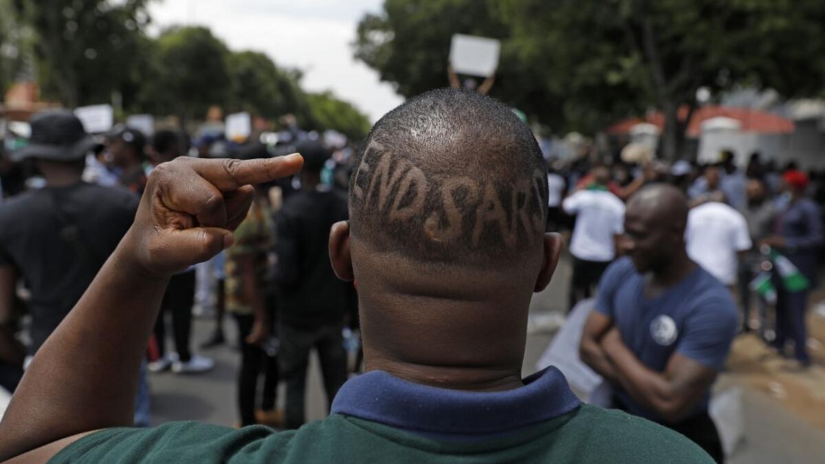 A Nigerian based in South Africa shows the middle finger and words "EndSars" shaved on his head during a protest outside the Nigerian embassy in Pretoria on October 21, 2020 in solidarity with Nigerian youth who are demanding an end to police brutality in the form of The Nigerian Police Force Unit, Special Anti-Robbery Squad (SARS). Phill Magakoe / AFP