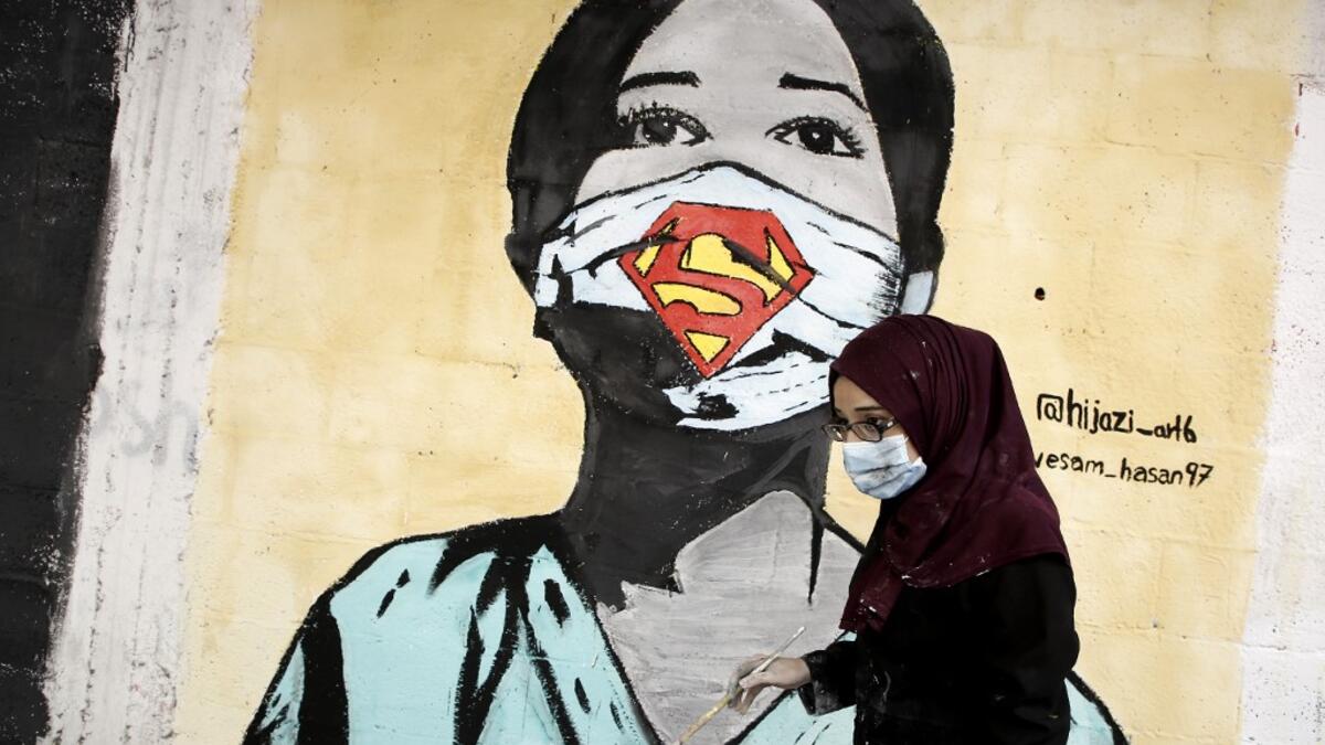 A Palestinian artist paints a mural of a mask-clad schoolgirl in Gaza City on October 22, 2020, amid the novel coronavirus pandemic crises. Mohammed ABED / AFP