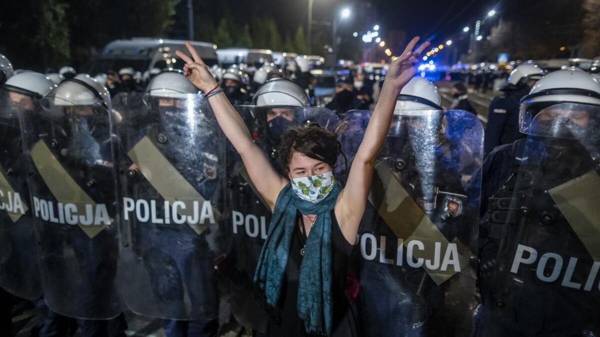 A protestor shows the V sign in front of a line of riot police guarding the house of Jaroslaw Kaczynski, leader of Poland's ruling Law and Justice party (PIS) during a demonstration against a decision by the Constitutional Court on abortion law restriction,in Warsaw on October 23, 2020. Wojtek RADWANSKI / AFP