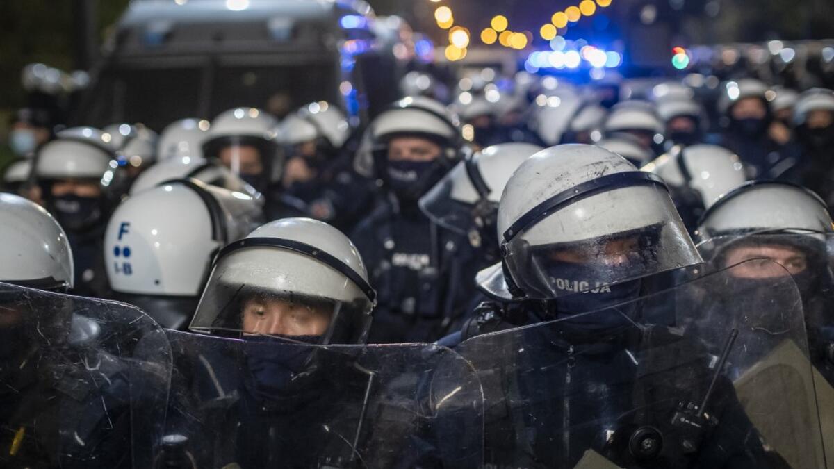 Riot police guarding the house of Jaroslaw Kaczynski, leader of Poland's ruling Law and Justice party (PIS) watch protestors during a demonstration against a decision by the Constitutional Court on abortion law restriction,in Warsaw on October 23, 2020. Wojtek RADWANSKI / AFP