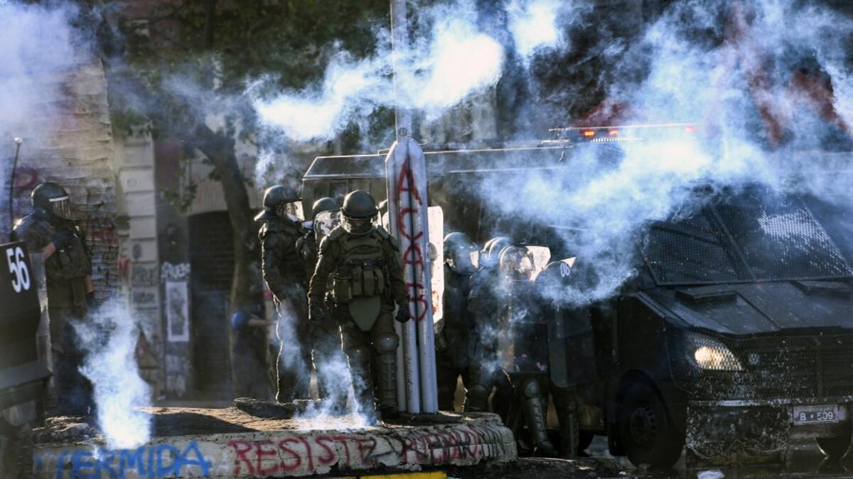 Demonstrators clash with riot police during a protest against Chilean President Sebastian Pinera's government on the constitutional referendum voting day at Plaza Italia square in Santiago on October 25, 2020. A year to the day after more than one million people thronged downtown Santiago in the biggest Chile's social uprising, Chileans vote Sunday on whether to change the country's dictatorship-era constitution seen as underpinning the nation's glaring inequalities. MARTIN BERNETTI / AFP