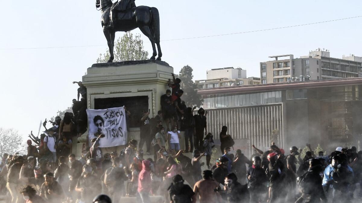 Demonstrators clash with riot police during a protest against Chilean President Sebastian Pinera's government on the constitutional referendum voting day at Plaza Italia square in Santiago on October 25, 2020. A year to the day after more than one million people thronged downtown Santiago in the biggest Chile's social uprising, Chileans vote Sunday on whether to change the country's dictatorship-era constitution seen as underpinning the nation's glaring inequalities. MARTIN BERNETTI / AFP