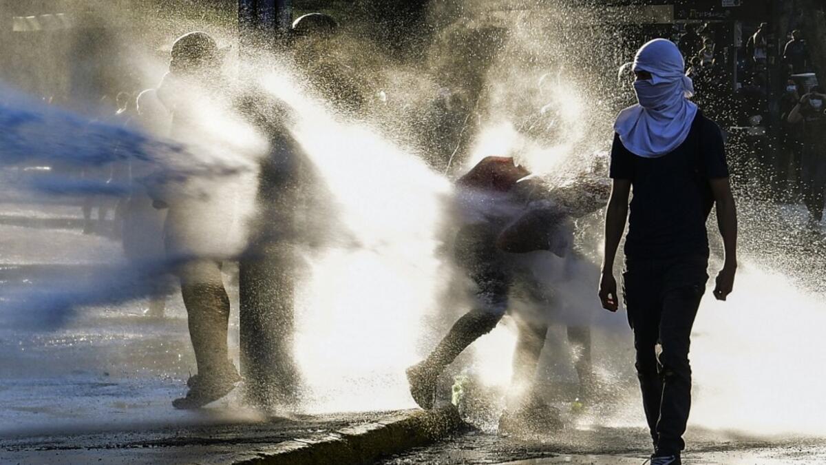 Demonstrators clash with riot police during a protest against Chilean President Sebastian Pinera's government on the constitutional referendum voting day at Plaza Italia square in Santiago on October 25, 2020. A year to the day after more than one million people thronged downtown Santiago in the biggest Chile's social uprising, Chileans vote Sunday on whether to change the country's dictatorship-era constitution seen as underpinning the nation's glaring inequalities. MARTIN BERNETTI / AFP
