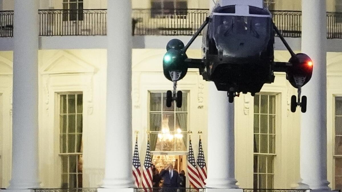 U.S. President Donald Trump stands on the Blue Room Balcony as Marine One takes off from the South Lawn of the White House on October 5, 2020 in Washington, DC. Trump was treated for Covid-19 at Walter Reed National Military Medical Center. Drew Angerer/Getty Images/AFP Drew Angerer / GETTY IMAGES NORTH AMERICA / Getty Images via AFP