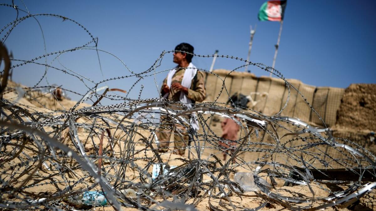 In this photo taken on September 27, 2020, a policeman keeps watch as he stands outside an outpost set up against Taliban fighters at Aziz Abad village in Maiwand district of Kandahar province. The dry and dusty village of Aziz Abad in Maiwand district sits on the frontline of Afghanistan's war and is currently under government control -- but only just. WAKIL KOHSAR / AFP