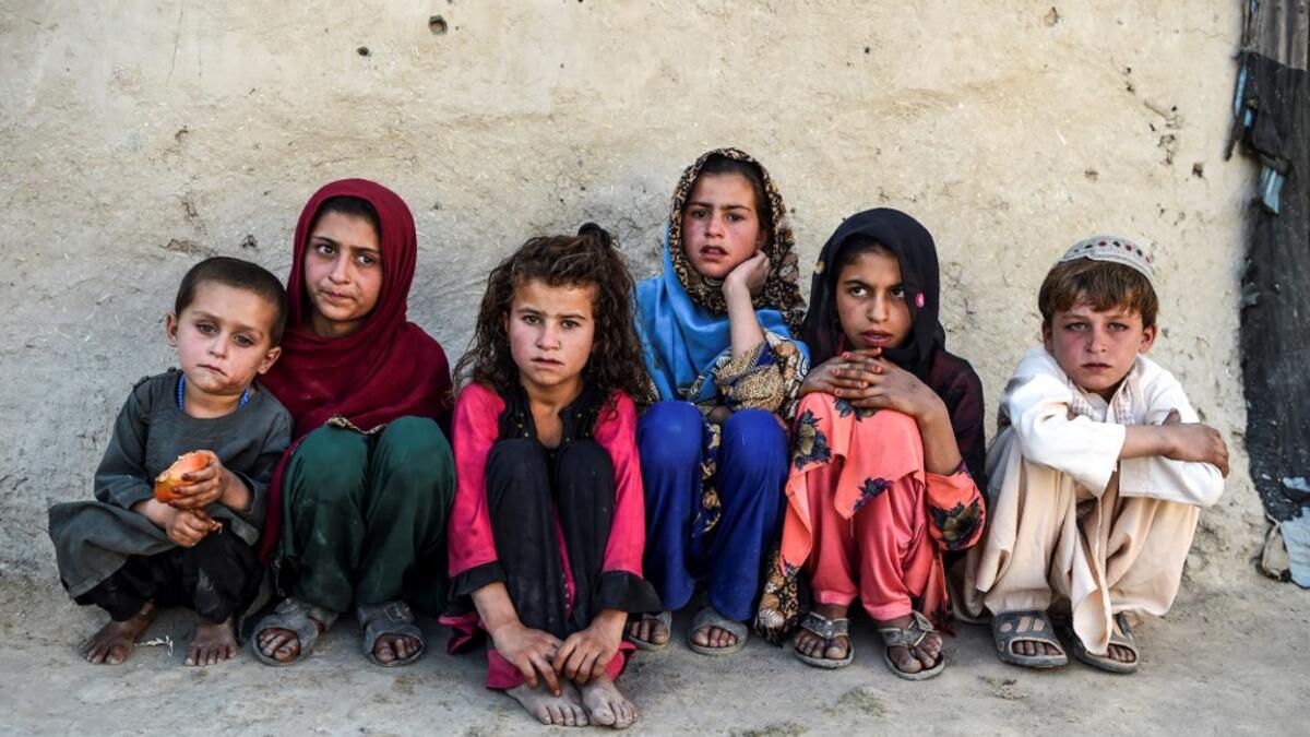 In this photo taken on September 27, 2020, children sit in front of a house at Deh Qubad village in Maiwand district of Kandahar province. The dry and dusty village of Aziz Abad in Maiwand district sits on the frontline of Afghanistan's war and is currently under government control -- but only just. WAKIL KOHSAR / AFP