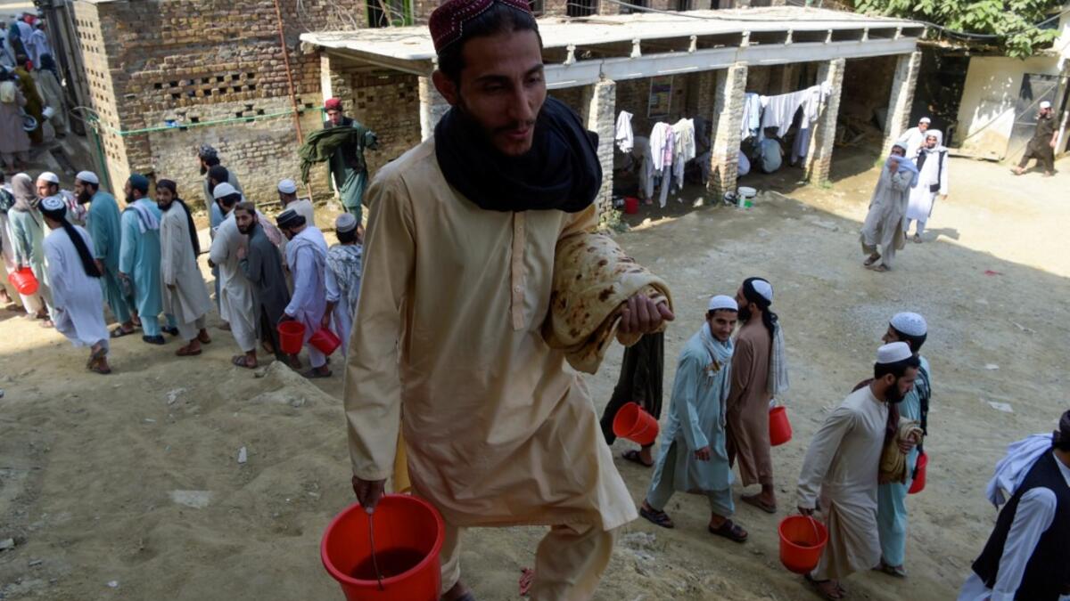 In this picture taken on October 19, 2020 Islamic seminary students wait to collect food at the Darul Uloom Haqqania seminary in Akora Khattak. The Darul Uloom Haqqania seminary has churned out a who's who of Taliban top brass -- including many now on the hardline group's negotiating team holding talks with the Kabul government to end a 20-year war. Abdul MAJEED / AFP