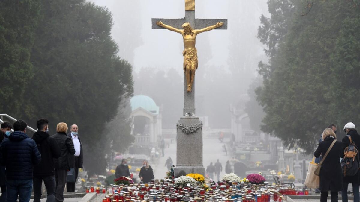 Faithfuls gather near the central cross, where candles have been laid, at the Mirogoj Cemetery in Zagreb, on November 1, 2020 to mark All Saints' Day. Every year on All Saints' Day, Croatian citizens visit and arrange the graves of their families. This year, due to the coronavirus pandemic, the usual crowds in cemeteries were absent, as citizens heeded the recommendation of the authorities to avoid mass gatherings. DENIS LOVROVIC / AFP