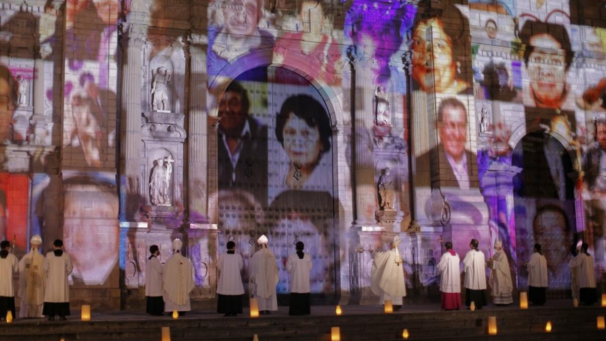 View of COVID-19 victims pictures proyected on the Lima Cathedral during a candlelight open-air mass with no public at the Plaza de Armas Main Square, in Lima on November 1, 2020 in remembrance of the more than 34,000 deceased from the coronavirus pandemic in Peru. The mass was conducted during the commemoration of the All Saints' Day under the projected images of elderly, children, firefighters, nurses, policemen, military victims of COVID-19 in Peru. Since the pandemic arrived in marchs to the country mor