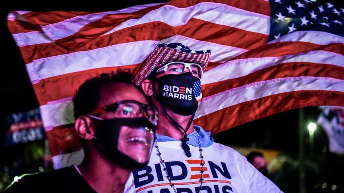 Alex Suarez (L) and Ralph Reichard (R) supporters of the Democratic party cheer as they attend a watch party in Miami, Florida on November 3, 2020. The US is voting Tuesday in an election amounting to a referendum on Donald Trump's uniquely brash and bruising presidency, which Democratic opponent and frontrunner Joe Biden urged Americans to end to restore "our democracy." CHANDAN KHANNA / AFP