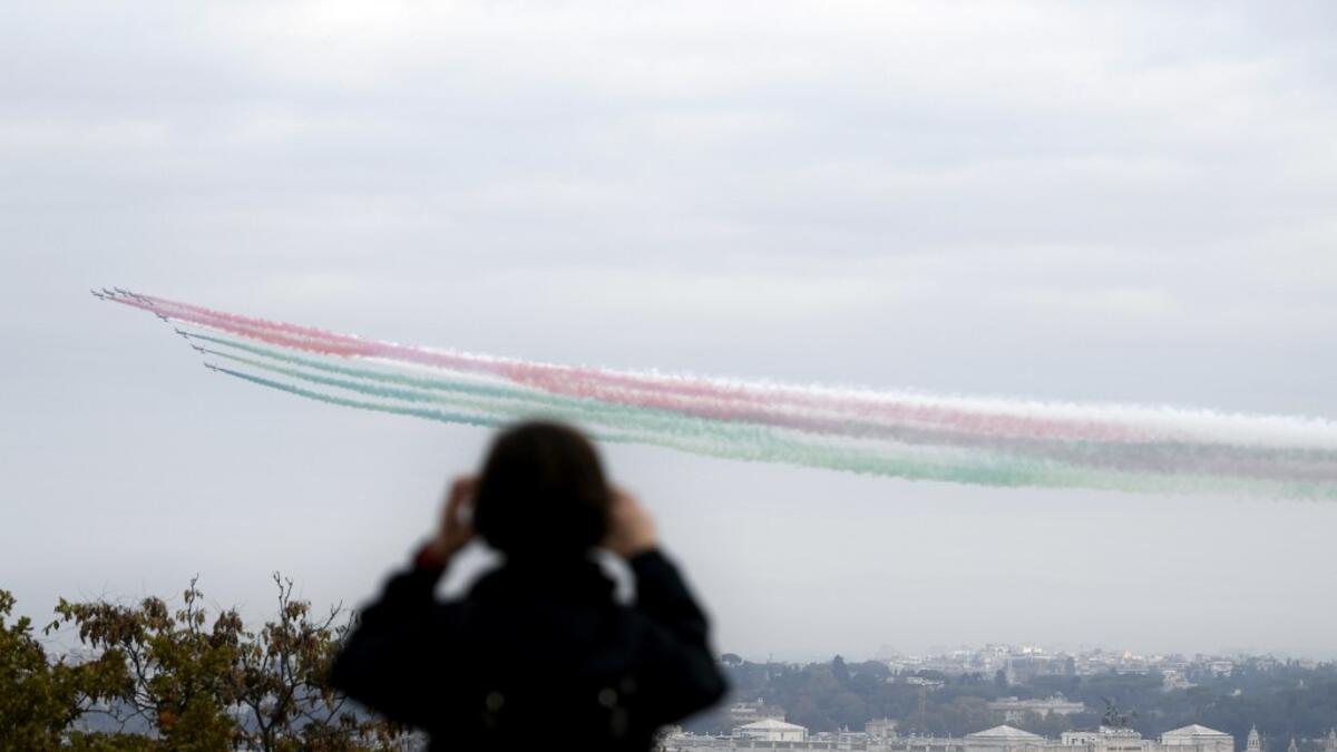 An onlooker takes a picture of the jets of the Italian Air Force aerobatic unit Frecce Tricolori (Tricolor Arrows) spreading smoke with the colors of the Italian flag as they fly over the city of Rome during the Armed Forces Day marking the end of World War I for Italy, on November 4, 2020. Filippo MONTEFORTE / AFP
