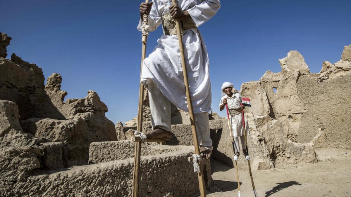 Egyptian school children dressed in traditional outfits, walk with stilts during a celebration to mark the inauguration of the fortress of Shali following its restoration, in the Egyptian desert oasis of Siwa, some 600 kms southwest of the capital Cairo, on November 6, 2020. Khaled DESOUKI / AFP
