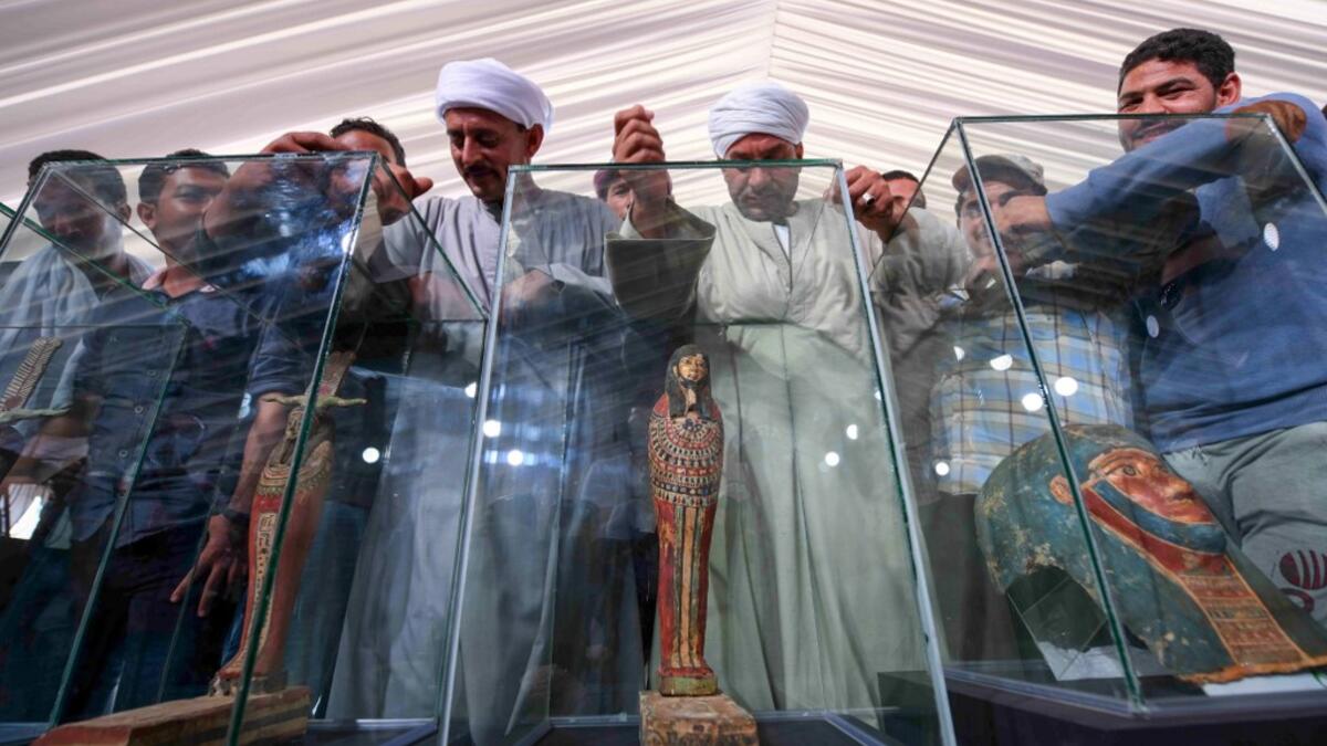 A picture shows statues and funerary masks on display during the unveiling of an ancient treasure trove of more than a 100 intact sarcophagi, at the Saqqara necropolis 30 kms south of the Egyptian capital Cairo, on November 14, 2020. Egypt announced the discovery of an ancient treasure trove of more than a 100 intact sarcophagi, the largest such find this year. The sealed wooden coffins, unveiled on site amid fanfare, belonged to top officials of the Late Period and the Ptolemaic period of ancient Egypt. Th