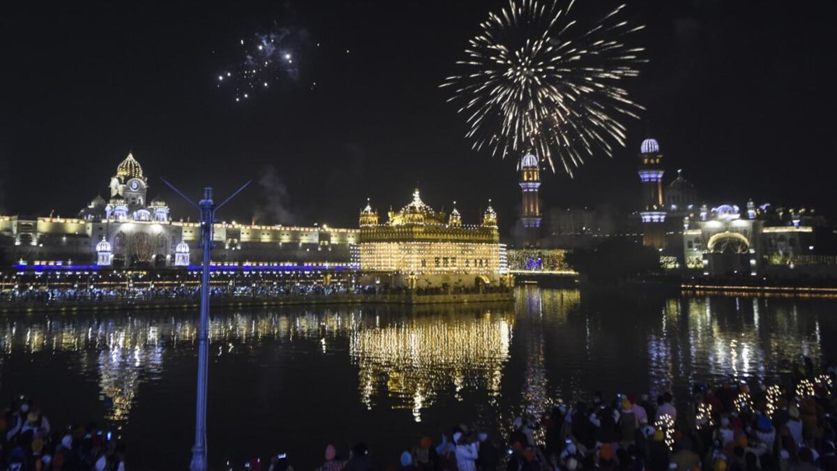 Sikh devotees watch as fireworks explode on the occasion of Bandi Chhor Divas, a Sikh festival coinciding with Diwali, the Hindu festival of light, over the Golden Temple in Amritsar on November 14, 2020. NARINDER NANU / AFP