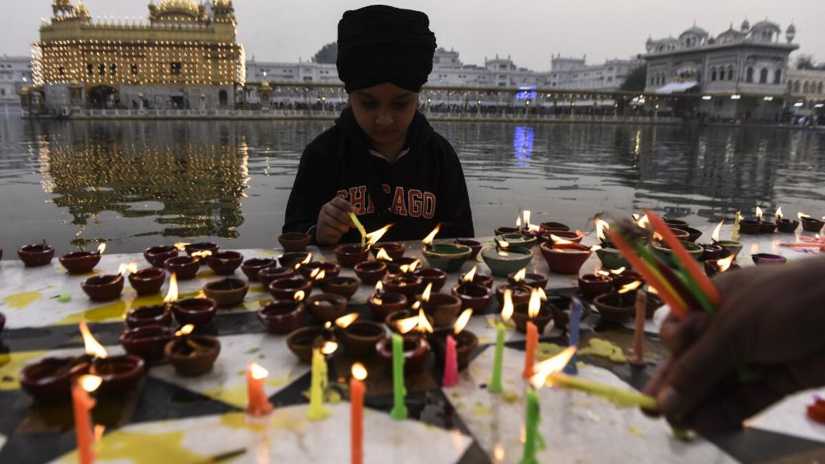 A Sikh boy lights oil lamps on the occasion of Bandi Chhor Divas, a Sikh festival coinciding with Diwali, the Hindu festival of Light, at the Golden Temple in Amritsar on November 14, 2020. NARINDER NANU / AFP