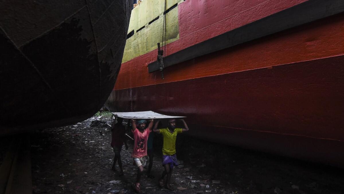 In this picture taken on November 16, 2020 dockyard workers carry a metal sheet during maintenance works for a ship on the banks of the Buriganga River in Char Kaliganj on the outskirts of Dhaka. Rivers are the lifeblood of the delta nation of 168 million people where much of the low-lying land is accessed via boat, with Bangladesh's strong economic growth of recent years fuelling more investments in new and bigger ships. Munir UZ ZAMAN / AFP