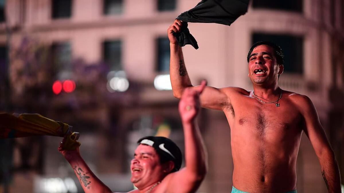 Fans wave their shirts in tribute to Maradona last night as they gathered by the Obelisk in the Argentinian capital. (AFP/File)