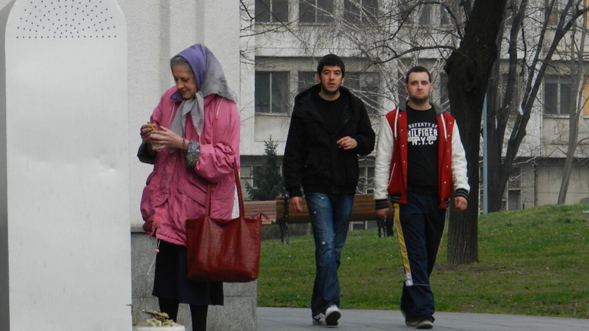 An elderly woman lights candles outside  the Temple of Saint Sava in Belgrade, Serbia /Photo by Ewelina Lepionko