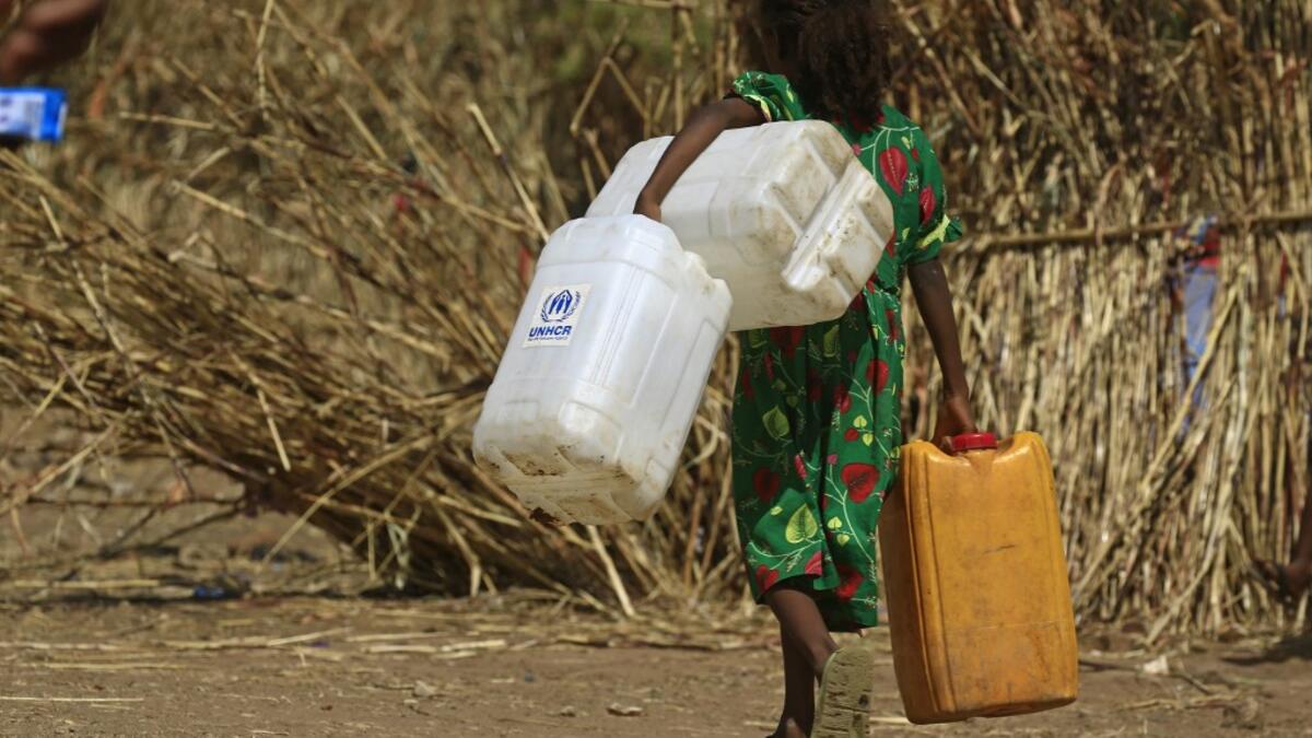 An Ethiopian refugee girl walks carrying water containers at Um Raquba camp in Sudan's eastern Gedaref province on November 28, 2020. Sudan needs $150 million in aid to cope with the flood of Ethiopian refugees crossing its border from conflict-stricken Tigray, the UN refugee agency chief said during a visit to a camp. ASHRAF SHAZLY / AFP