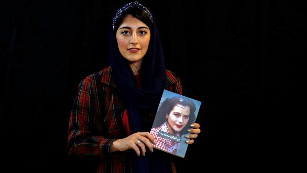 Employee Parisa Agha Mohammadi poses with a bestselling book of the Saless Publishing House in Iran's capital Tehran, on October 11, 2020. ATTA KENARE / AFP
