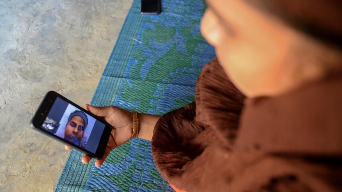 In this photograph taken on October 13, 2020, Rohingya refugee Umme Khair, who gave money to a community leader to travel to Malaysia to her husband, interacts with her spouse via video call at a makeshift shelter in Kutupalong Rohingya refugee in Ukhia. Stay in a squalid refugee camp -- hopeless, starving, and made to feel a burden -- or leave, risking death, rape, human trafficking and months at sea to reach a husband you've never met. This is the bleak choice many Rohingya women, already scarred from fle