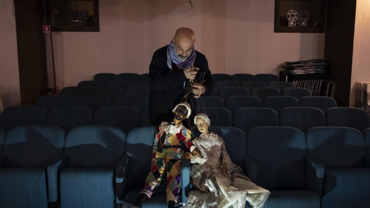 Marco Grilli holds two puppets in the parterre at the " Alfa Theatre" in Turin, on November 30, 2020. The Grilli family has a collection of more than 20,000 objects from around the world, everything from theatres, marionettes and glove puppets to shadow figures and silhouettes. A long-time dream of Grilli and his wife Mariarosa, 78, the museum is due to open in 2023 in Turin, financed both privately and publicly with the help of different institutions.  Marco Bertorello / AFP
