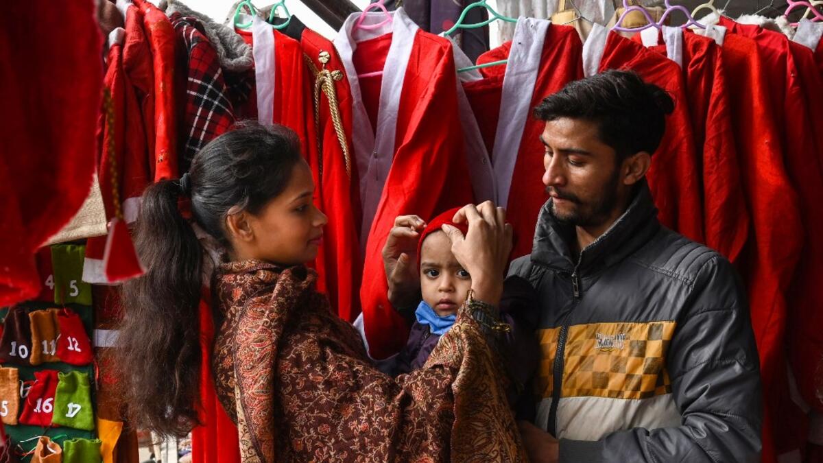 In this picture taken on December 15, 2020, a Christian family buys a Santa Claus outfit for their son at a shop ahead of Christmas celebrations in Lahore. Arif ALI / AFP