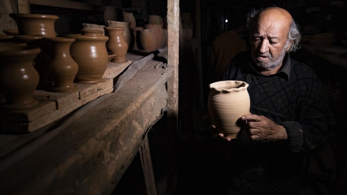 Syrian-Armenian potter Misak Antranik Petros arranges pottery vases at his workshop located inside an ancient mud-brick house near the city of Qamishli in Syria's northeastern Hasakeh province, on December 19, 2020. Petros was only a teenager when he had to take over for his sick father and become the main potter of the family. He has since become a master of the craft, and is keen to pass his skills on.  Delil SOULEIMAN / AFP