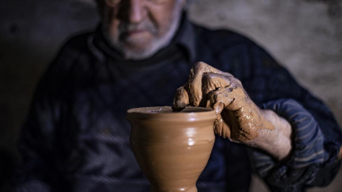 Syrian-Armenian potter Misak Antranik Petros uses an ancient pottery wheel to churn different types of pots at his workshop located inside an ancient mud-brick house near the city of Qamishli in Syria's northeastern Hasakeh province, on December 19, 2020. Petros was only a teenager when he had to take over for his sick father and become the main potter of the family. He has since become a master of the craft, and is keen to pass his skills on.  Delil SOULEIMAN / AFP