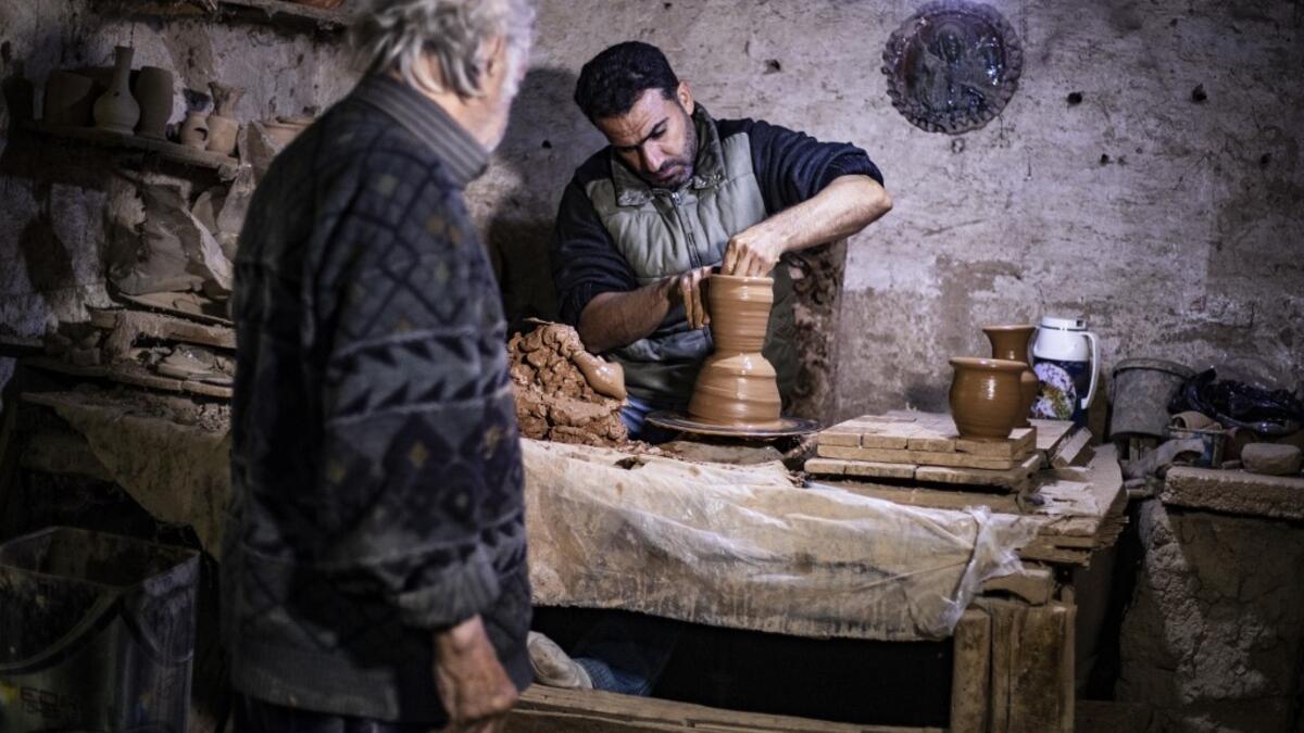 Syrian-Armenian potter Misak Antranik Petros watches his son Anto moulding a clay vase at his workshop located inside an ancient mud-brick house near the city of Qamishli in Syria's northeastern Hasakeh province, on December 19, 2020. Petros was only a teenager when he had to take over for his sick father and become the main potter of the family. He has since become a master of the craft, and is keen to pass his skills on.  Delil SOULEIMAN / AFP