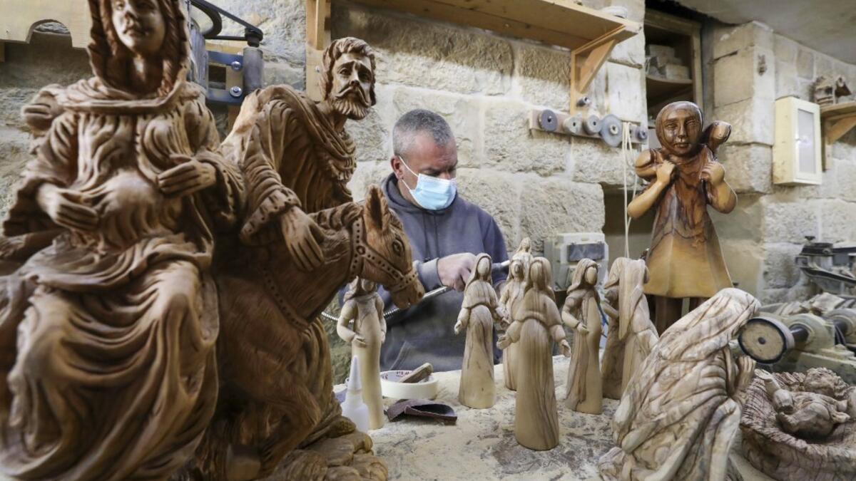 A Palestinian carpenter carves religious statues and figurines from olive wood at a shop near the Church of the Nativity, in the West Bank city of Bethlehem on December 21, 2020. HAZEM BADER / AFP