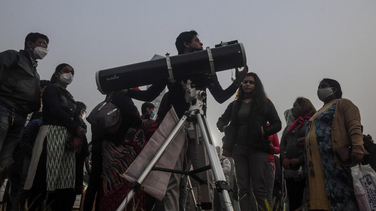 People stand in a queue to see a 'great conjunction' of Jupiter and Saturn at the Maidan area in Kolkata on December 21, 2020. Dibyangshu SARKAR / AFP