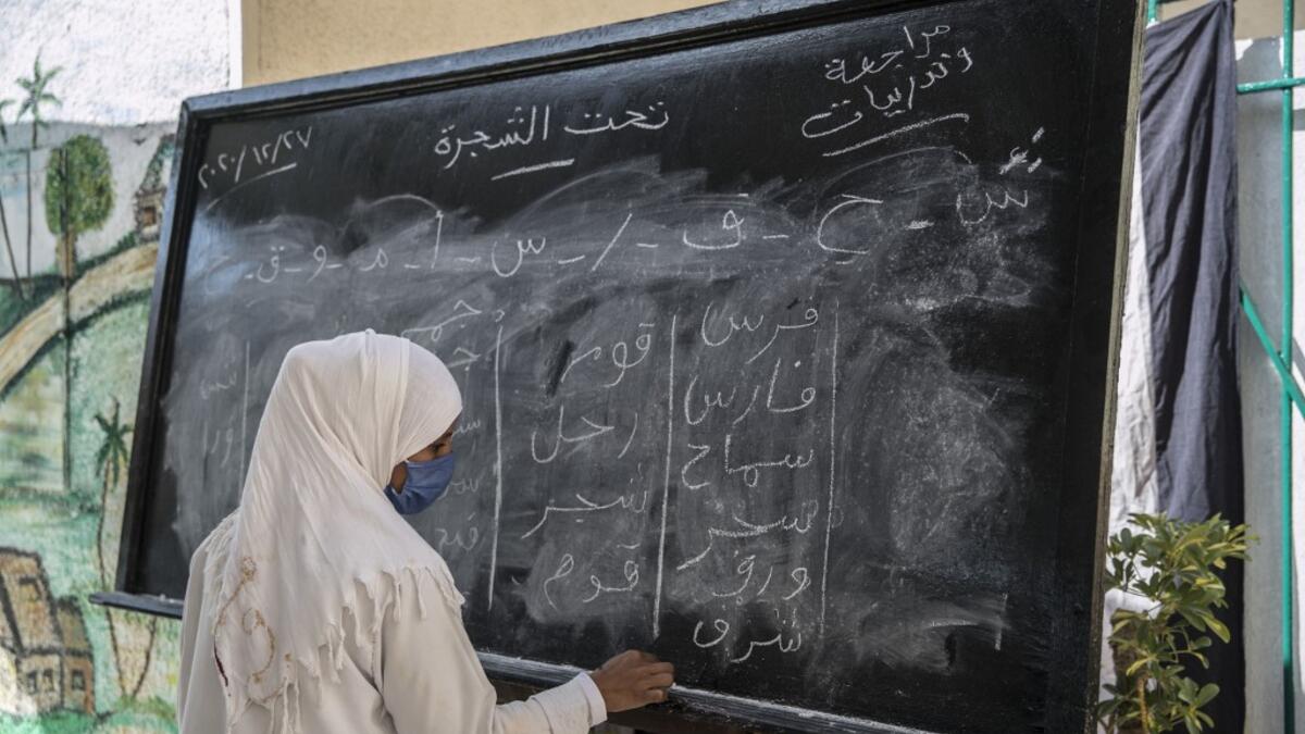 This picture taken during a government-guided tour on December 27, 2020 shows an inmate writing on a blackboard during a literacy class at al-Qanatir women's prison, at the tip of the Nile delta in Qalyoubiya province, about 30 kilometres north of Egypt's capital. Khaled DESOUKI / AFP