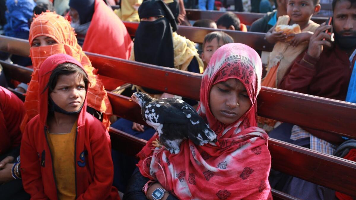 A Rohingya refugee holds a hen on a Bangladesh Navy ship as she sits with others being relocated to the controversial flood-prone island Bhashan Char in the Bay of Bengal, in Chittagong on December 29, 2020. Rehman ASAD / AFP