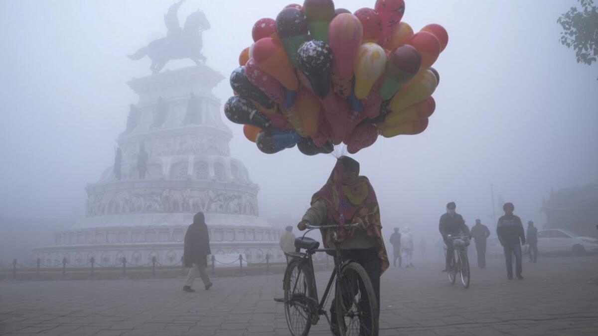 A balloon seller walks along Heritage street amid dense fog on a cold day on New Year's Day, in Amritsar on January 1, 2021. NARINDER NANU / AFP