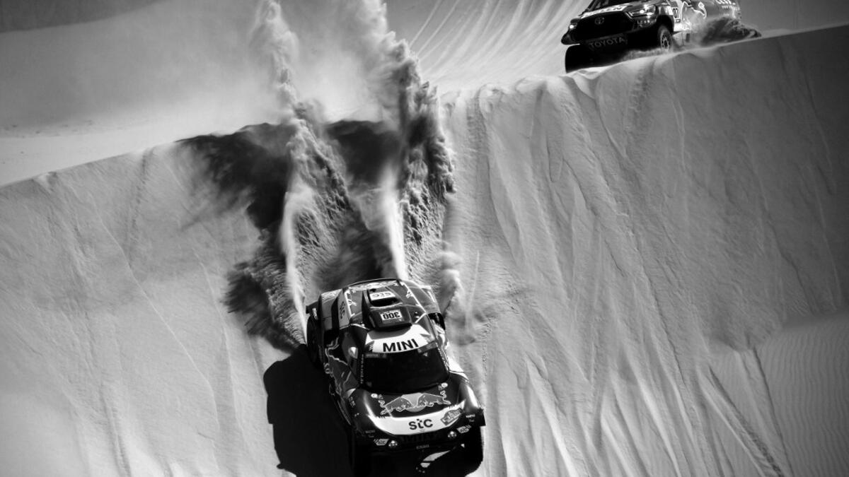 Mini's Spanish drivers Carlos Sainz of Spain and co-driver Lucas Cruz of Spain (L) overtake Toyota's driver Jakub Przygonski of Poland and his co-driver Timo Gottschalk of Germany (R) compete during Stage 3 of the Dakar Rally 2021 around Wadi Ad-Dawasir, in Saudi Arabia, on January 5, 2021. FRANCK FIFE / AFP