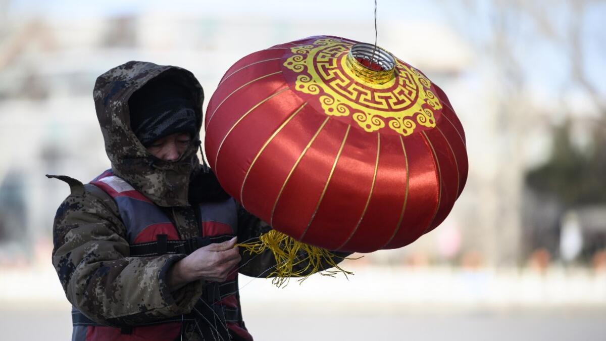 A worker installs a lantern by the icy Lake Houhai in Beijing on January 7, 2021, after China's meteorological authority recently issued a severe weather warning across large parts of the country. NOEL CELIS / AFP