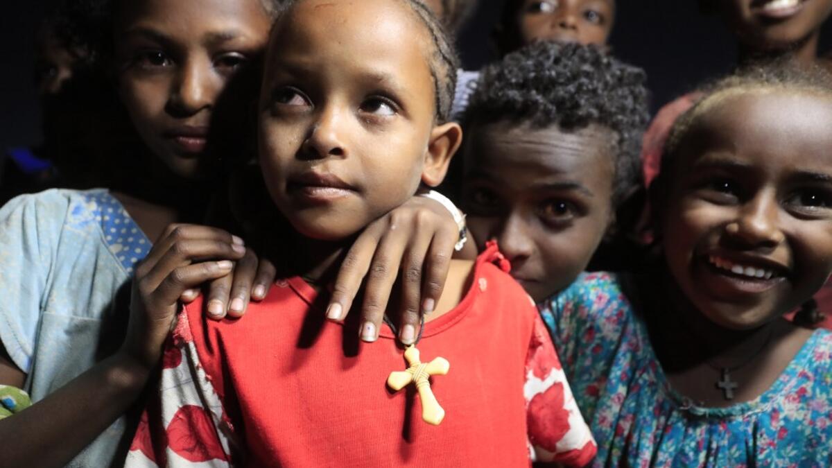 Ethiopian refugee children who fled the Tigray conflict attend the Coptic Christmas midnight mass with local believers, in front of an Ethiopian Orthodox church built by former Ethiopian refugees, at a village next to Um Raquba refugee camp in Gedaref, eastern Sudan, late on January 6, 2021. ASHRAF SHAZLY / AFP